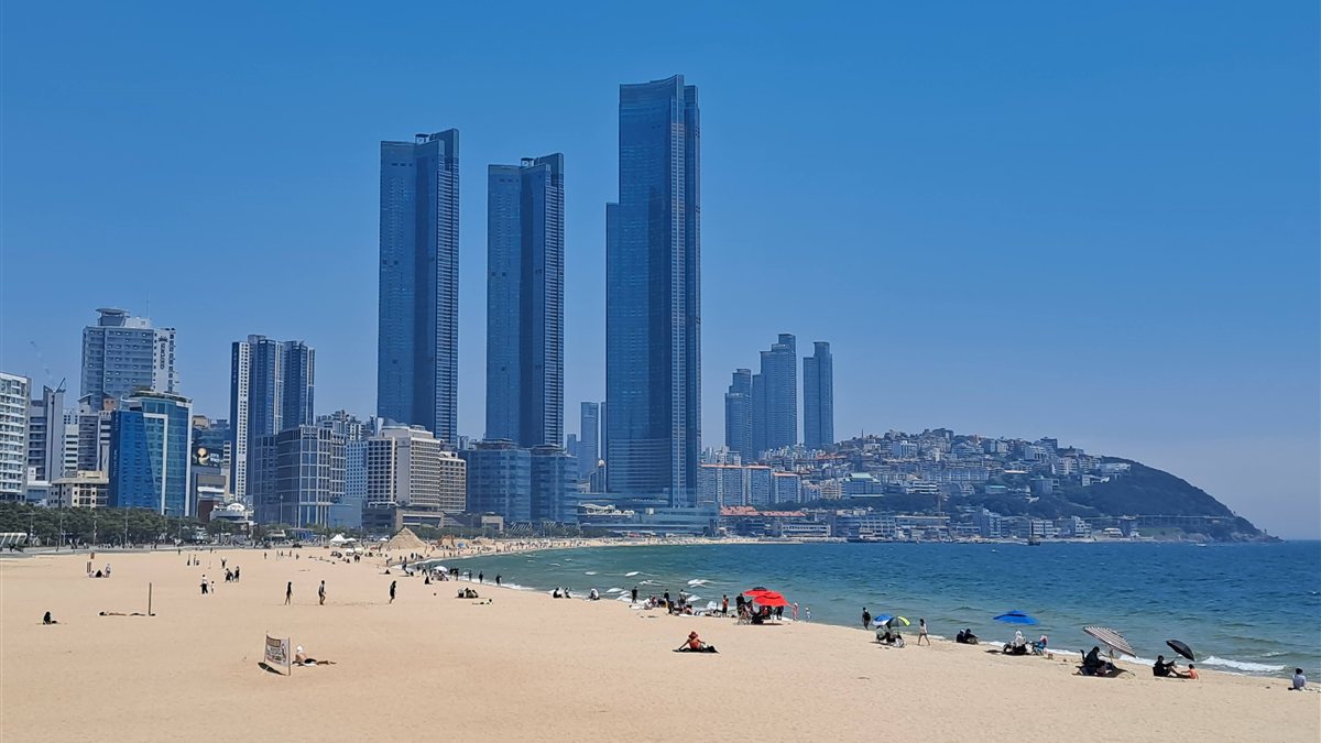 Haeundae Beach with sand in the foreground and tall buildings along the shore