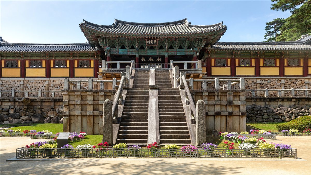 The stone staircases leading up to a gate at Bulguksa Temple, with flower beds in front