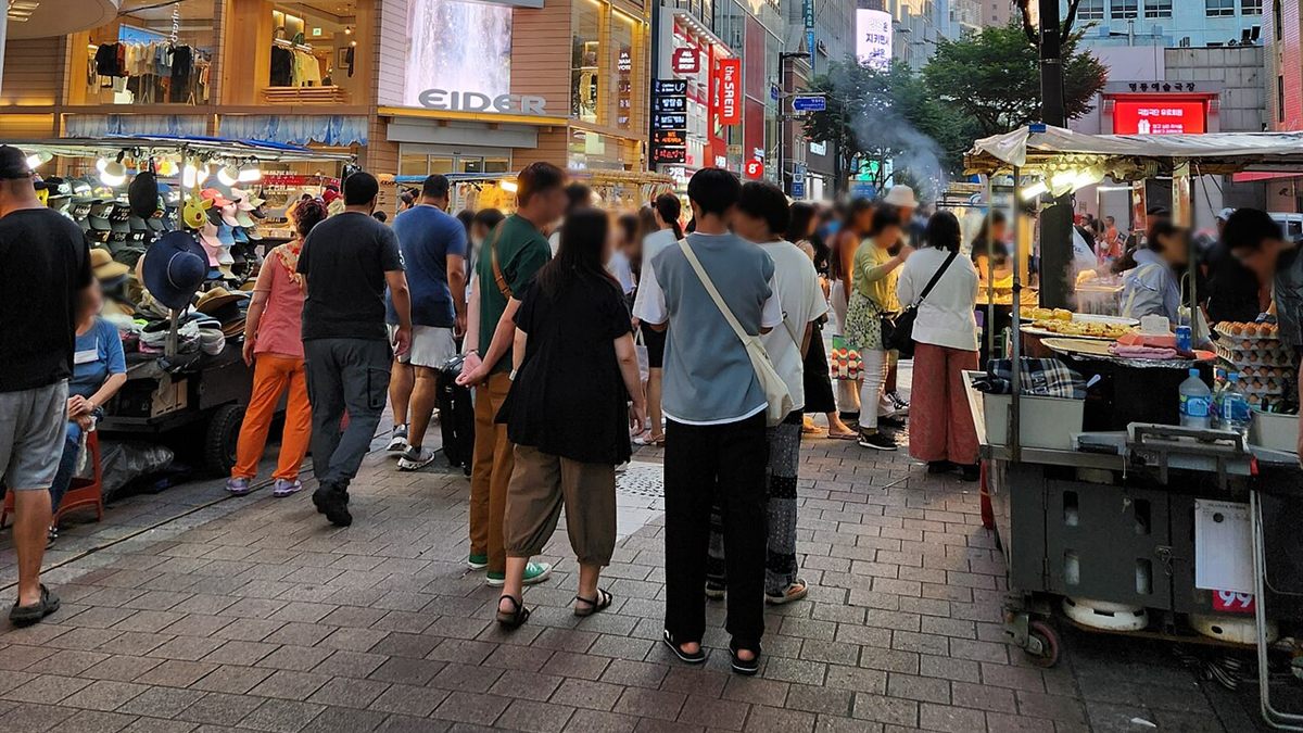 Street-food stalls and shoppers on Myeongdong 7-gil in Seoul in the early evening